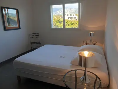 a bedroom with a bed with a lamp and a window at Maison au calme avec vue magnifique in Sari Solenzara