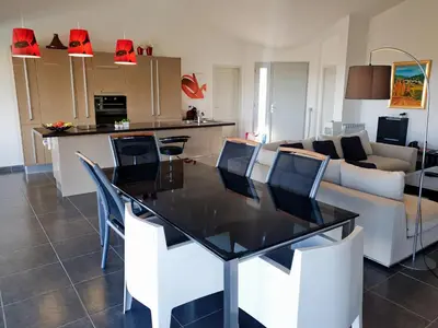 a kitchen and living room with a table and a couch at Maison au calme avec vue magnifique in Sari Solenzara