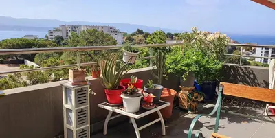 a balcony with potted plants and a bench at T3 vue mer proche plage in Ajaccio