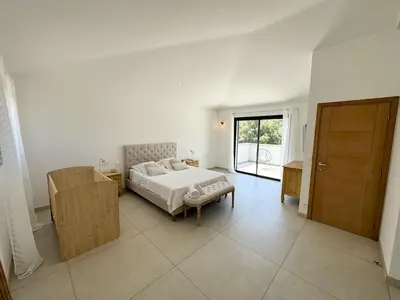 a white bedroom with a bed and a sliding door at Villa - Porto-Vecchio - Piscine privée in Porto-Vecchio