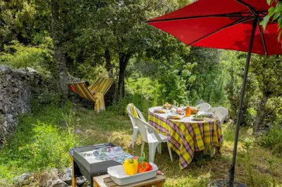 a table and chairs with a red umbrella in a yard at Casa Di Babbo in Olmi-Cappella