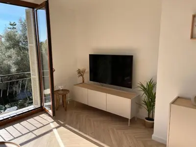a living room with a flat screen tv on a white wall at Charmant appartement T2 hypercentre à Ajaccio in Ajaccio