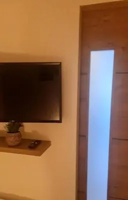 a flat screen tv on a wall next to a door at New Superbe F2 refait à neuf tout confort avec piscine et mer à pied in Serra-di-Ferro