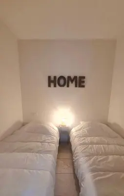 two beds in a room with a home sign on the wall at New Superbe F2 refait à neuf tout confort avec piscine et mer à pied in Serra-di-Ferro