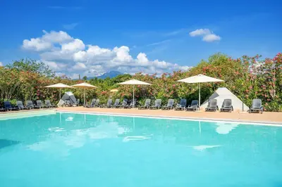 a large swimming pool with chairs and umbrellas at Camping Domaine d'Anghione in Castellare-di-Casinca