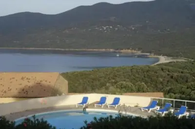 a swimming pool with chairs and a view of a lake at Villa 4 à 5 pers T2 climatisée & wifi résidence piscine et mer à pied in Serra-di-Ferro