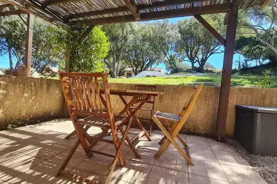 a wooden table and two chairs on a patio at Villa 4 à 5 pers T2 climatisée & wifi résidence piscine et mer à pied in Serra-di-Ferro