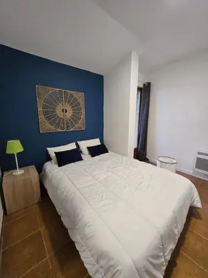 a large white bed in a room with a blue wall at Villa 4 à 5 pers T2 climatisée & wifi résidence piscine et mer à pied in Serra-di-Ferro