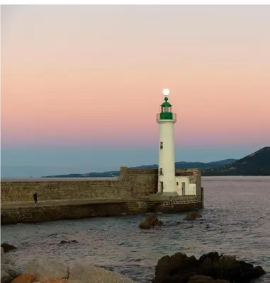 a lighthouse sitting on top of a pier in the water at Charmant T2 lumineux avec terrasse in Propriano