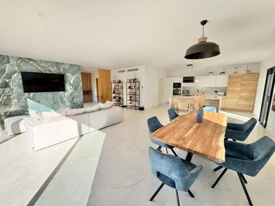 a living room with a wooden table and blue chairs at Villa Porto-Vecchio avec piscine in Lecci