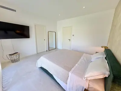 a white bedroom with a bed and a flat screen tv at Villa Porto-Vecchio avec piscine in Lecci