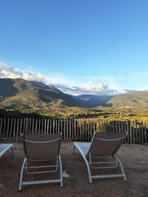 two chairs sitting on a patio with mountains in the background at Tradition Corse & Modernité I Caseddi di Barabè in Granace