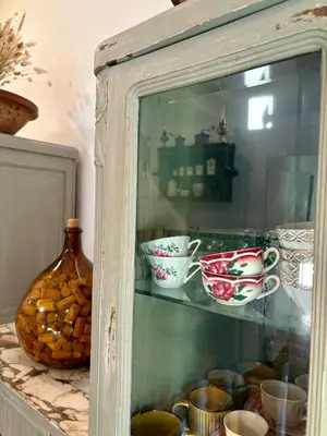 a glass cabinet with bowls and cups and a vase at Tradition Corse & Modernité I Caseddi di Barabè in Granace