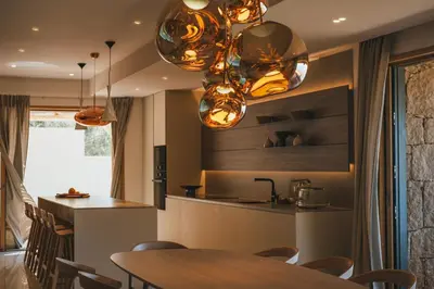 a kitchen with a wooden table and some lights at Casi di Mare in Cargèse