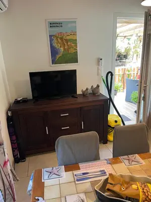 a living room with a television and a table with chairs at Bonifacio tranquillité paradis in SantʼAmanza