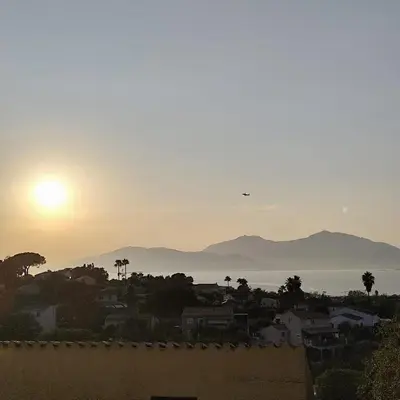 a view of the sun setting over a city at Bella Vista 4, T2 vue mer, piscine, climatisé Porticcio in Porticcio