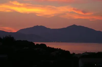 a sunset over the water with mountains in the background at Bella Vista 4, T2 vue mer, piscine, climatisé Porticcio in Porticcio