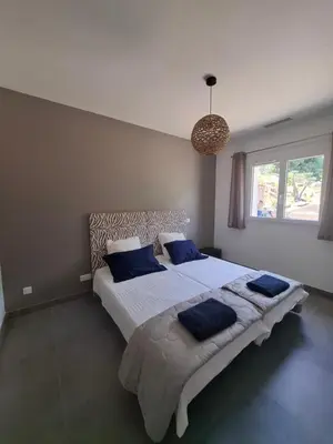 a bedroom with a large bed with blue pillows at Domaine Le Chemin des Oliviers jusqu'à 12 personnes piscine et ou jacuzzi in Ocana