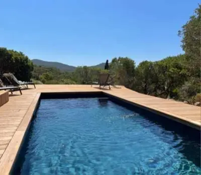 a swimming pool with blue water and a bench at Maison de standing avec piscine vue mer Corse du sud Pozzaccio, Portigliolo 2 à 6 personnes 3 chambres in Coti-Chiavari