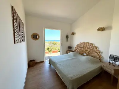 a bedroom with a bed and a large window at Villa vue mer, spacieuse, piscine privée in Sari Solenzara