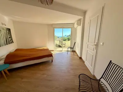 a bedroom with a bed and two chairs and a window at Villa vue mer, spacieuse, piscine privée in Sari Solenzara