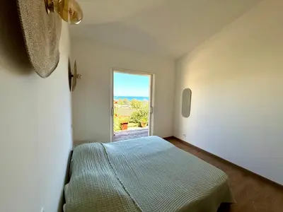 a bedroom with a bed and a window at Villa vue mer, spacieuse, piscine privée in Sari Solenzara