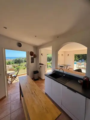 a kitchen with a counter top and a table at Villa vue mer, spacieuse, piscine privée in Sari Solenzara