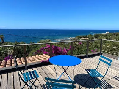 a blue table and chairs on a deck with the ocean at Maison à 50 m de la plage, 10 personnes, 5 chambres en corse du sud, in Coti-Chiavari
