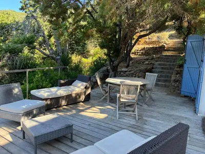 a wooden deck with chairs and a table and chairs at Maison à 50 m de la plage, 10 personnes, 5 chambres en corse du sud, in Coti-Chiavari