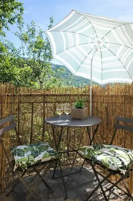a table and two chairs with an umbrella at Maison typique de village Corse , 10 min aéroport et de la mer in Prunelli-di-Casacconi