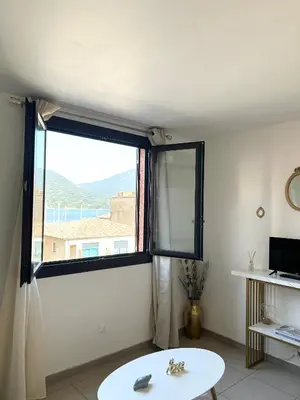 a living room with a large window and a table at Joli T2 petite vue mer in Propriano