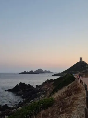 a beach with a lighthouse on a hill next to the ocean at Appartement Ajaccio vue mer in Ajaccio