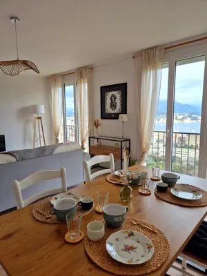 a dining room table with plates and bowls on it at Appartement Ajaccio vue mer in Ajaccio