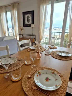 a dining room table with plates and glasses on it at Appartement Ajaccio vue mer in Ajaccio