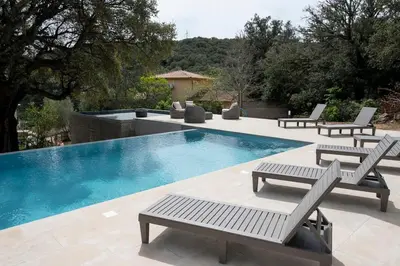 a swimming pool with two chairs and avisorvisor at Noscia Nivaledda - Stone house, with pool in Porto-Vecchio