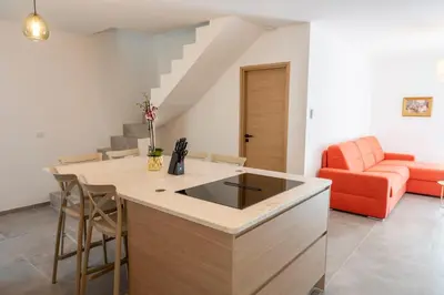 a kitchen with an island in a living room with an orange couch at Noscia Nivaledda - Stone house, with pool in Porto-Vecchio