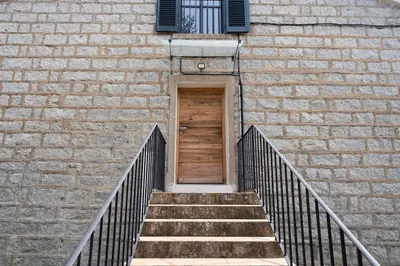 a staircase leading to a brick building with a wooden door at Noscia Nivaledda - Stone house, with pool in Porto-Vecchio