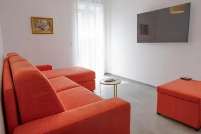 a living room with an orange couch and a stool at Noscia Nivaledda - Stone house, with pool in Porto-Vecchio