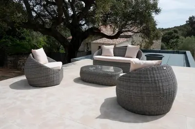 three wicker chairs and a table on a patio at Noscia Nivaledda - Stone house, with pool in Porto-Vecchio