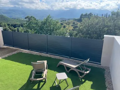 a patio with two chairs and a table on a lawn at E casette in Oletta