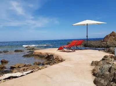 a pair of chairs and an umbrella on a beach at Secret creek in Zonza
