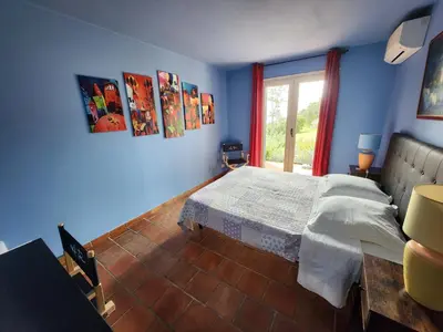 a blue room with a bed and a window at Secret creek in Zonza