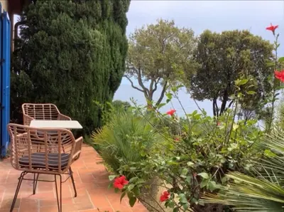 a patio with two chairs and flowers and trees at Secret creek in Zonza