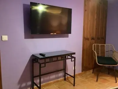 a tv on a wall with a table and a chair at Secret creek in Zonza