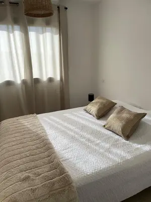 a white bed with two pillows on top of it at Magnifique appartement T2 in Cuttoli-Corticchiato