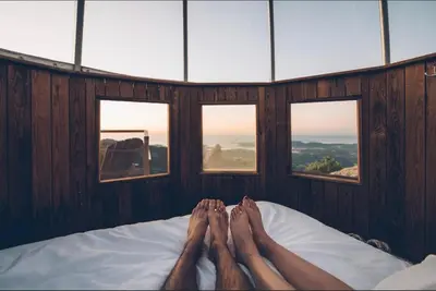 a person laying on a bed in a room with windows at Cocoon Village in Porto-Vecchio