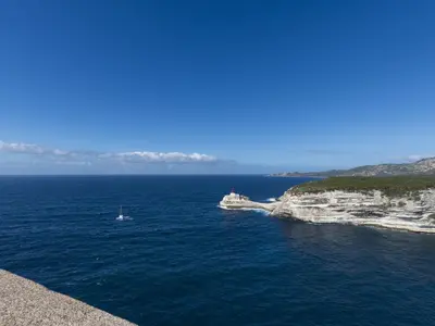 a boat in the water next to an island at Apartment Foce Dell Edera-2 by Interhome in Bonifacio