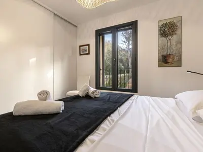 a white bedroom with a large bed with a window at Apartment Foce Dell Edera-1 by Interhome in Bonifacio