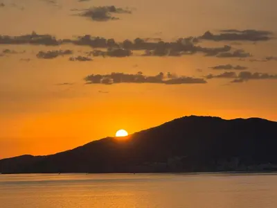 a sunset over a mountain with the sun setting behind it at Superbe maison F5 avec vue mer - Plage à 5 min - Climatisation - Wifi gratuit in Grosseto-Prugna