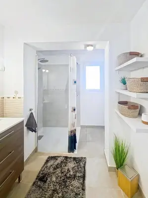 a white bathroom with a shower and a rug at Superbe maison F5 avec vue mer - Plage à 5 min - Climatisation - Wifi gratuit in Grosseto-Prugna